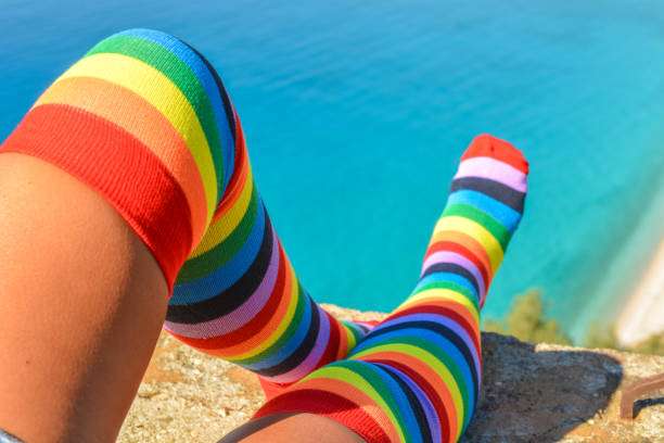 Colorful rainbow compression socks for women enjoying a scenic view by the vibrant blue ocean.