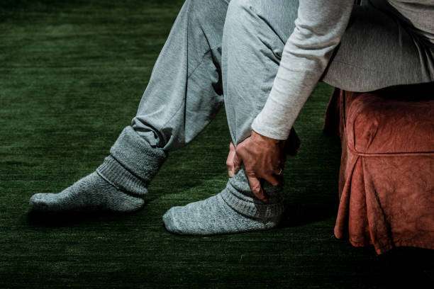 Person experiencing ankle pain, considering compression socks for women's leg support.