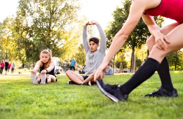 People exercising in park wearing compression socks for women, stretching.