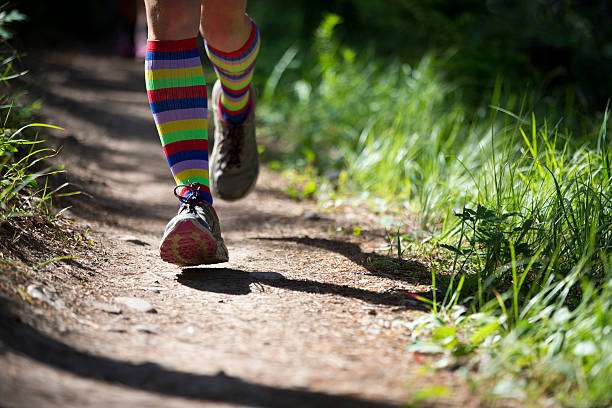 Close-up of a woman trail running wearing colorful striped compression socks for women.