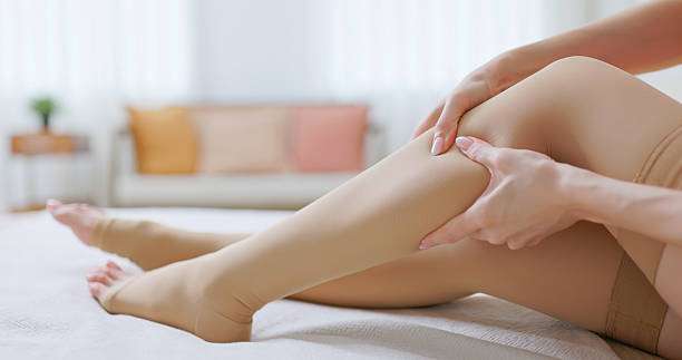 Woman adjusting her nude-colored compression socks for women while relaxing at home.