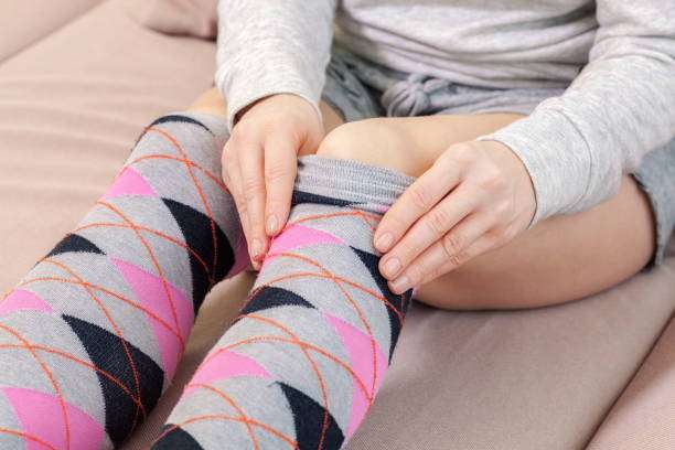 Woman adjusting argyle compression socks for women on her legs while sitting. Comfortable fit.