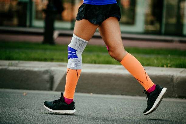 Woman running with orange compression socks for women and knee brace