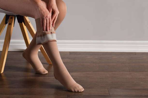Woman applying tan compression socks for women on her leg